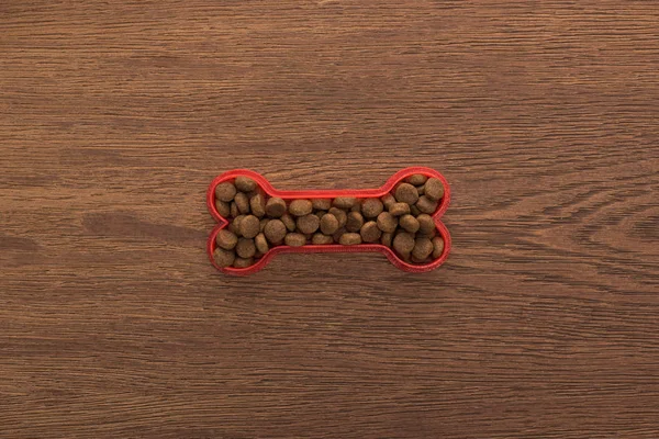 Vista superior de comida seca para mascotas en hueso sobre mesa de madera - foto de stock