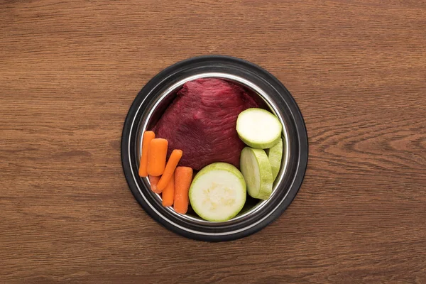 Ansicht von rohem Gemüse und Fleisch in Schüssel auf Holztisch — Stockfoto
