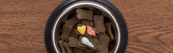 Top view of dry pet food in silver bowl with vitamins on wooden table, panoramic shot — Stock Photo