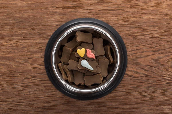 Vue du dessus des aliments secs pour animaux de compagnie dans un bol en argent avec des vitamines sur une table en bois — Photo de stock