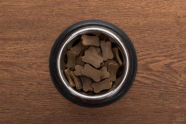 Vista superior de comida seca para mascotas en un tazón de plata sobre una mesa de madera - foto de stock