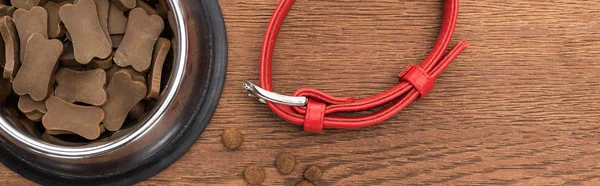 Top view of dry pet food in silver bowl near red collar on wooden table, panoramic shot — Stock Photo