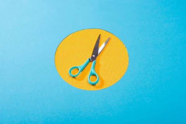High angle view of metal scissors on yellow circle — Stock Photo