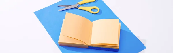 Panoramic shot of notebook, scissors and paper on white background — Stock Photo