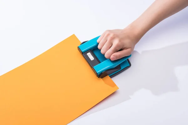 Cropped view of woman using holepunch on white background — Stock Photo