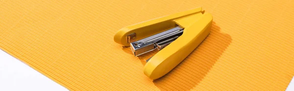 Panoramic shot of yellow stapler on bright paper isolated on white — Stock Photo