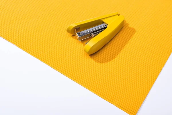 High angle view of yellow stapler on bright paper isolated on white — Stock Photo