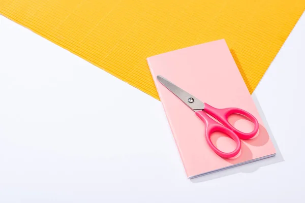 Vista de ángulo alto de tijeras, cuaderno y papel sobre fondo blanco - foto de stock