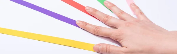 Panoramic shot of woman touching colorful paper strips on white background — Stock Photo