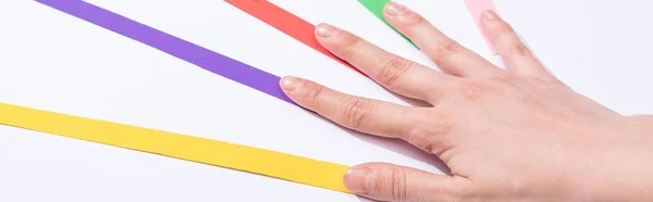 Plano panorámico de mujer tocando tiras de papel de colores sobre fondo blanco - foto de stock