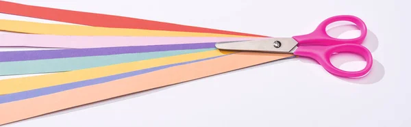 Panoramic shot of scissors and colorful paper strips on white background — Stock Photo