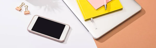 Panoramic shot of laptop, notebooks, pen, erasers, smartphone, paper clips and paper — Stock Photo