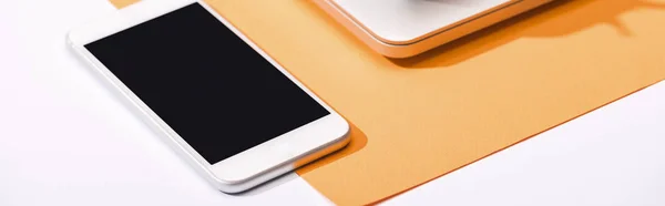 Panoramic shot of smartphone with copy space and orange paper — Stock Photo