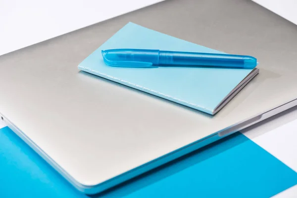 High angle view of colorful notebook, blue pen, laptop, paper on white background — Stock Photo