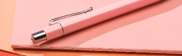 Panoramic shot of pen and notebook on orange paper — Stock Photo