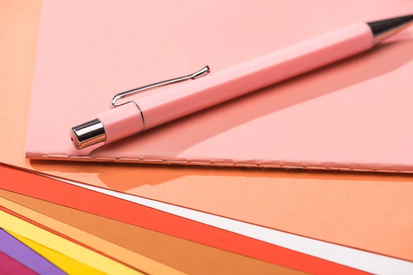 Mise au point sélective du stylo et du carnet sur des papiers lumineux et colorés — Photo de stock