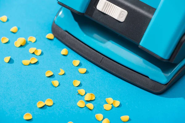 Visão de alto ângulo de holepunch com círculos de papel no fundo azul — Fotografia de Stock