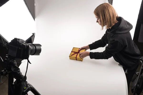 Hermoso fotógrafo tomando fotos de regalo de Navidad en la cámara digital en blanco en el estudio de fotos - foto de stock