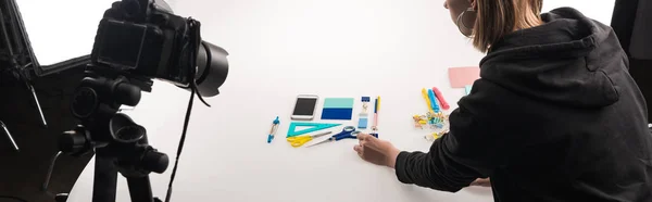 Vista recortada del fotógrafo haciendo plano con suministros de oficina para la sesión de fotos comerciales en blanco, plano panorámico - foto de stock