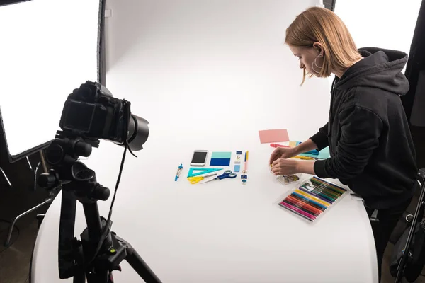 Photographer making flat lay with office supplies for commercial photo shooting on white — Stock Photo