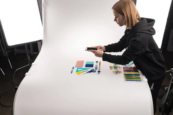 Fotógrafo comercial fazendo fotos de material de escritório no smartphone — Fotografia de Stock