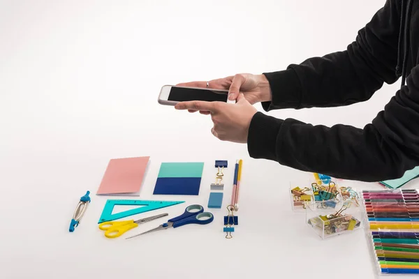 Cropped view of photographer making flat lay with office supplies for commercial photo shooting on smartphone — Stock Photo
