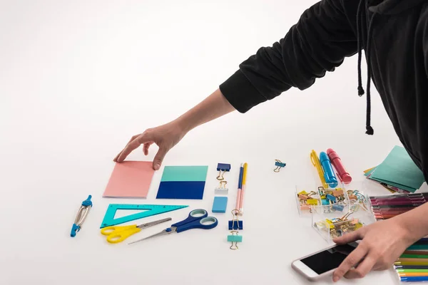 Cropped view of photographer making flat lay with office supplies for commercial photo shooting on smartphone — Stock Photo