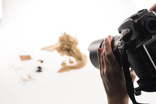 Vista ritagliata del fotografo scattare foto di composizione con flora e accessori sulla fotocamera digitale su bianco — Foto stock