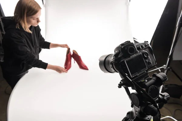 Fotógrafo haciendo sesión de fotos comerciales de zapatos de tacón rojo femenino en blanco - foto de stock