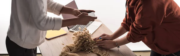 Cropped view of two commercial photographers taking pictures of composition with flora and accessories on smartphone — Stock Photo