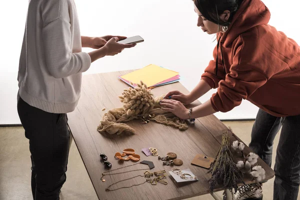 Two commercial photographers taking pictures of composition with flora and jewelry on smartphone — Stock Photo