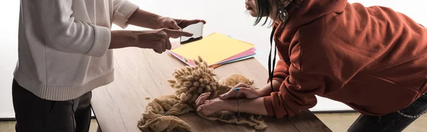 Cropped view of two commercial photographers taking pictures of composition with flora and accessories on smartphone — Stock Photo