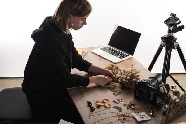 Photographer making composition with flora and accessories for photo shooting with camera and laptop — Stock Photo