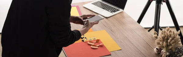 Cropped view of commercial photographer taking pictures of composition with flora and accessories on smartphone — Stock Photo