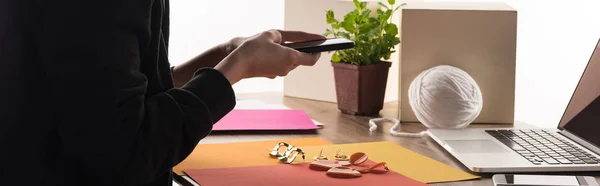 Cropped view of commercial photographer taking pictures of composition with accessories on smartphone — Stock Photo