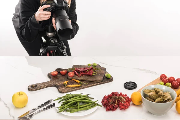 Cropped view of female photographer making food composition for commercial photography and taking photo on digital camera — Stock Photo