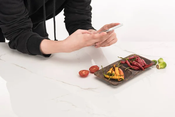 Zugeschnittene Ansicht eines Fotografen, der Nahrungsmittelkompositionen für kommerzielle Fotografie auf dem Smartphone herstellt — Stockfoto