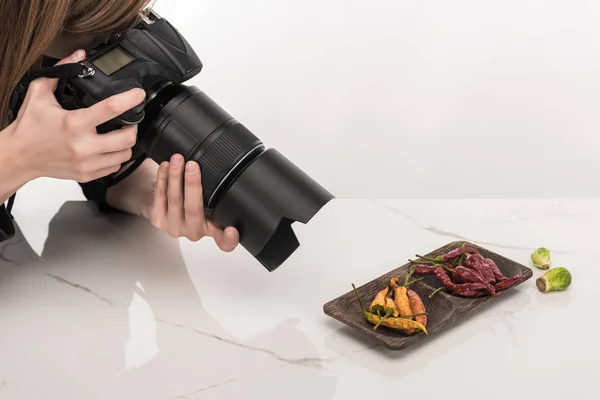 Vista ritagliata di fotografo femminile fare composizione alimentare per la fotografia commerciale e scattare foto sulla fotocamera digitale su bianco — Foto stock