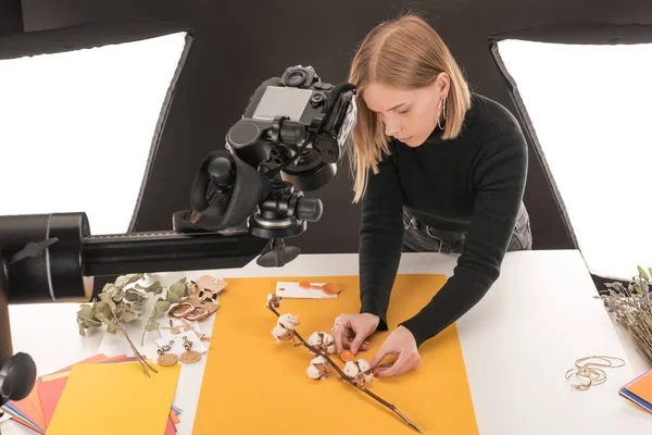 Joven fotógrafo haciendo composición con flor de algodón y accesorios para sesión de fotos - foto de stock