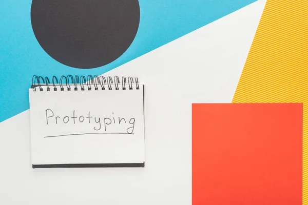 Top view of notebook with prototyping lettering on abstract geometric background — Stock Photo