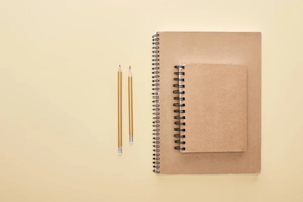 Tendido plano con cuadernos en blanco de papel con lápices sobre fondo beige - foto de stock
