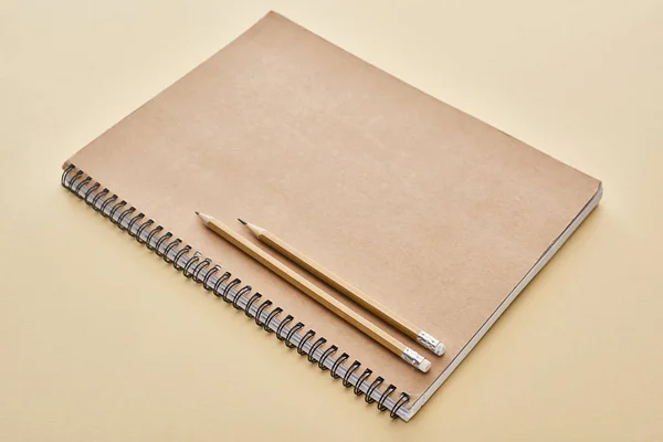 Паперовий блокнот з олівцями на бежевому тлі. — стокове фото