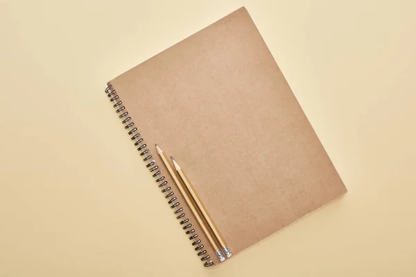 Vista superior de papel em branco notebook com lápis em fundo bege — Fotografia de Stock