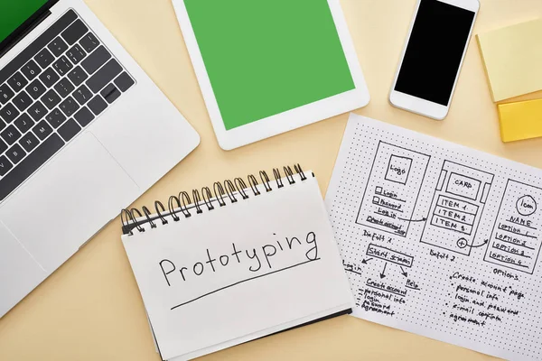 Draufsicht auf Gadgets in der Nähe von Website-Design-Vorlage und Notizbuch mit Prototyping-Schriftzug auf gelbem Hintergrund — Stockfoto