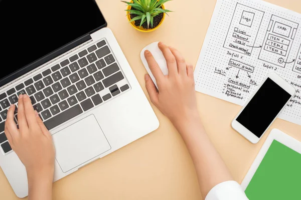 Teilansicht des Designers mit Laptop in der Nähe von Gadgets, Website-Design-Vorlage und grüner Pflanze auf beigem Hintergrund — Stockfoto