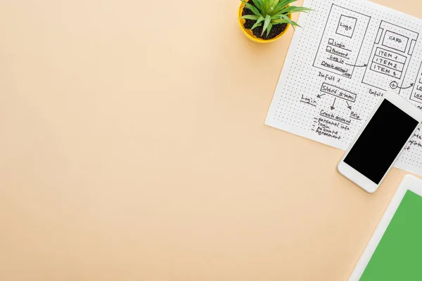 Top view of gadgets near website design template and green plant on beige background with copy space — Stock Photo