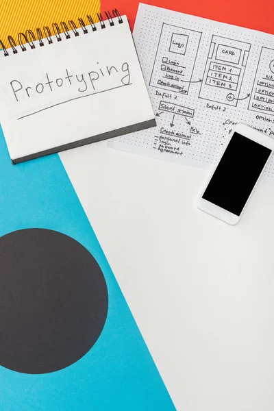 Draufsicht auf Notizbuch mit Prototyping-Schriftzug, Smartphone und Website-Design-Vorlage auf abstrakt geometrischem Hintergrund — Stockfoto