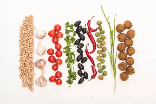 Vue de dessus du pois chiche, ail, tomates cerises, persil, olives, piment, oignon vert et falafel sur fond blanc — Photo de stock