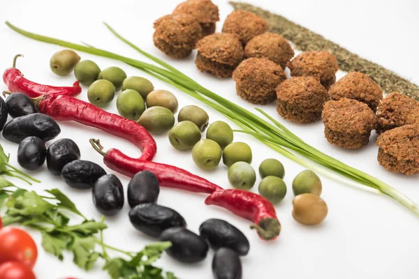 Vue rapprochée du persil, des olives, du piment, de l'oignon vert et du falafel sur fond blanc — Photo de stock