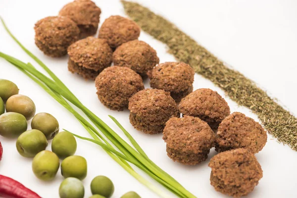 Vista de cerca de aceitunas, cebolla verde, hierba y falafel sobre fondo blanco - foto de stock
